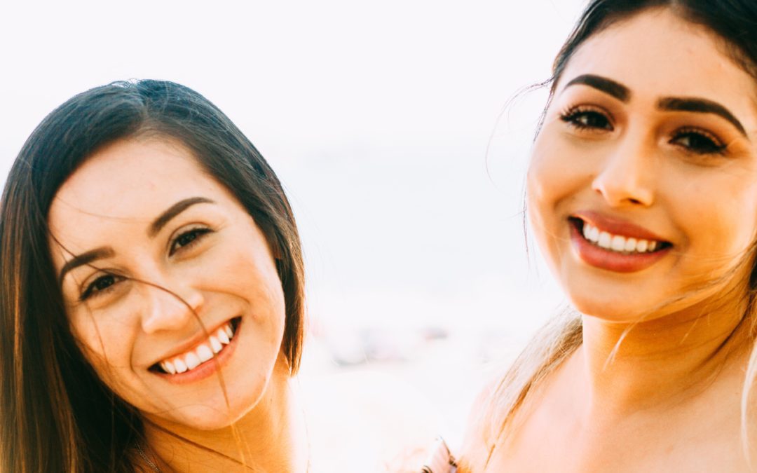 Two brunette females smiling with their teeth