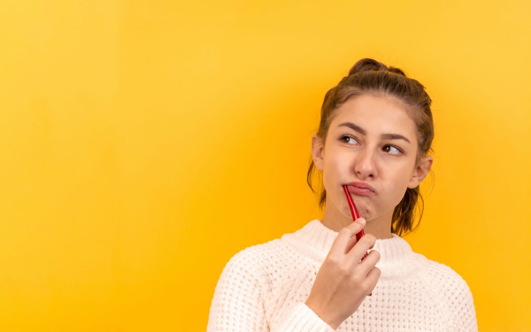 Portrait of a beautiful girl on a yellow background, who is brushing her teeth and is thinking about something.