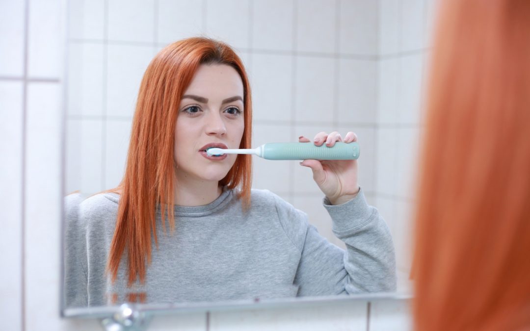 Woman brushing her teeth in the mirror